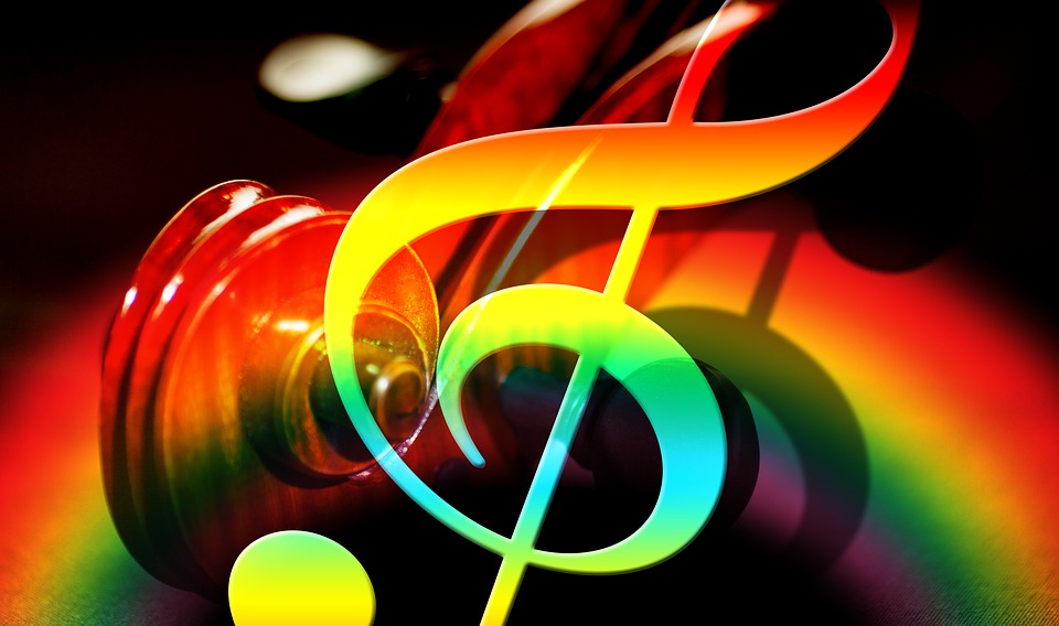 Image of treble clef and part of a violin. In the background there is a rainbow light effect.