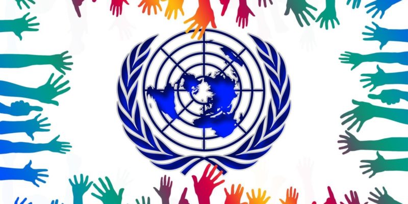 Symbol of UN, surrounded by many multicoloured hands